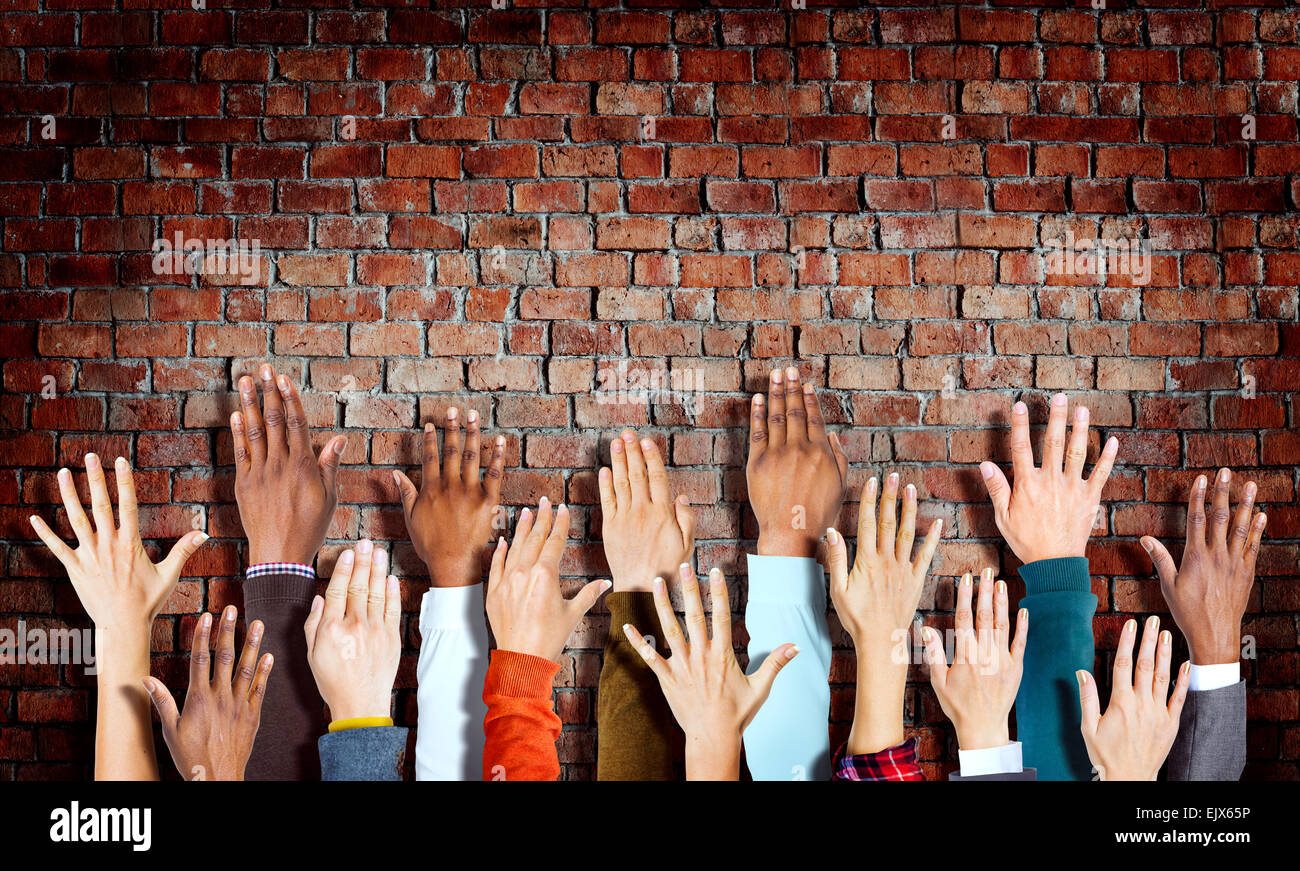 Gruppo di diverse mani sollevate su un muro di mattoni Foto Stock
