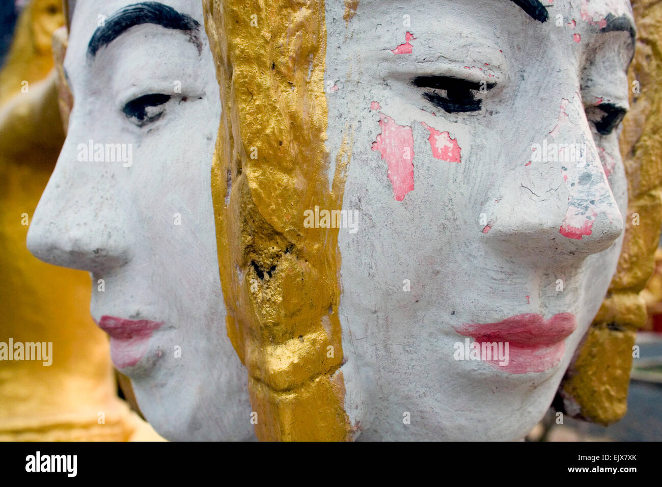 Le facce di colore rosa e bianco di fronte statue di Buddha sono in mostra in un tempio buddista in Kampong Cham, Cambogia. Foto Stock