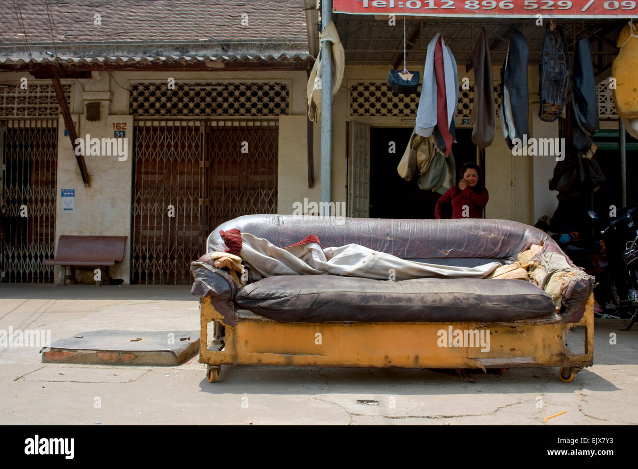 Un divano fatiscente poggia su un marciapiede davanti a un negozio di tappezzeria in Kampong Cham, Cambogia. Foto Stock