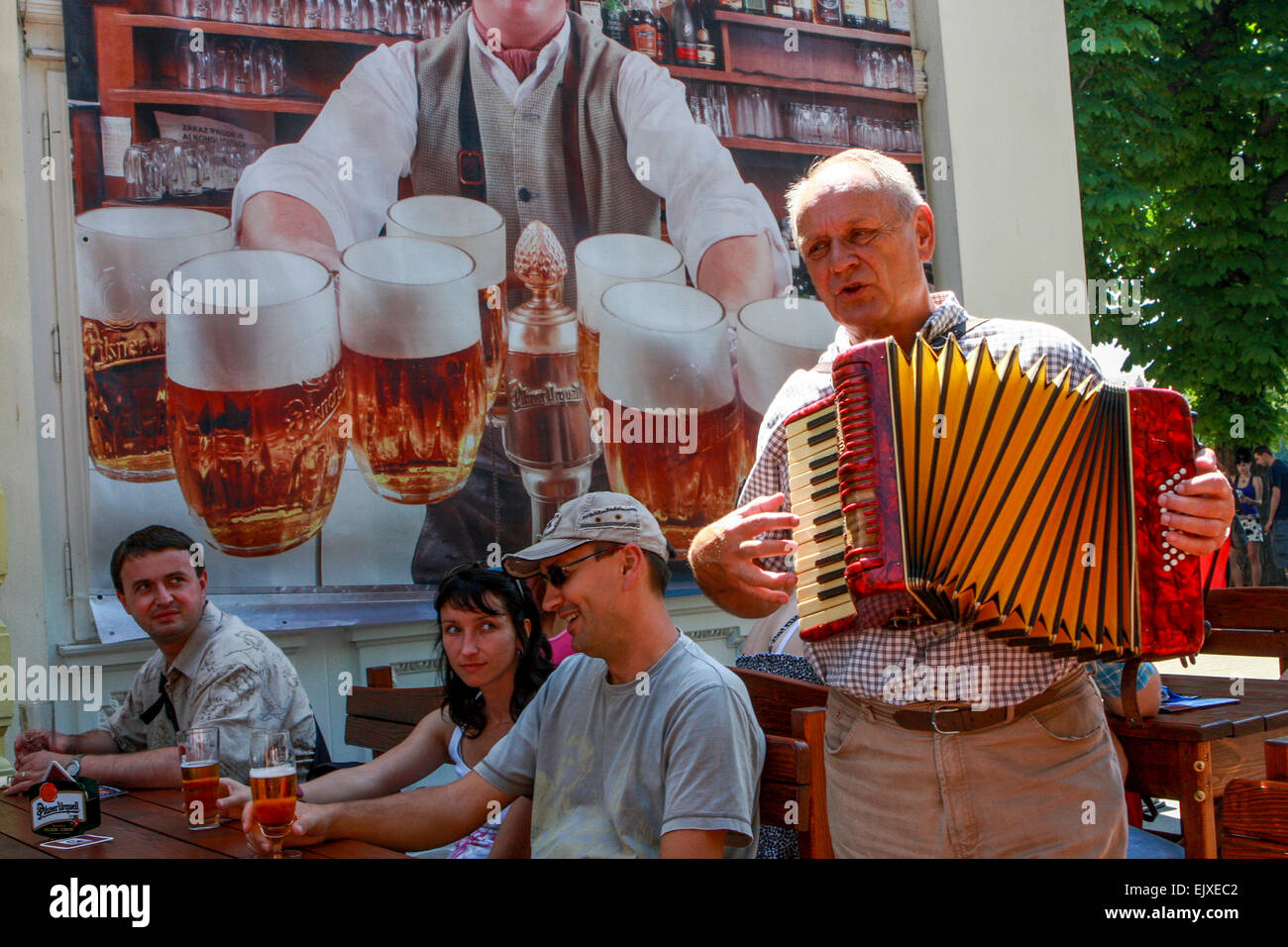 Birreria all'aperto di Praga, gente che beve birra Repubblica Ceca turismo Praga musicista uomo che suona la fisarmonica per le persone in un ristorante con giardino Foto Stock