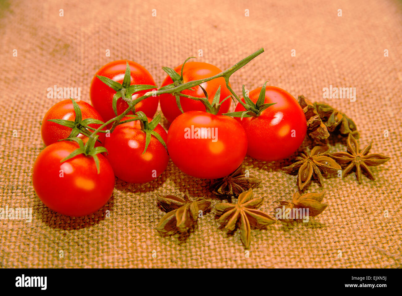 Un sacco rossi pomodori ciliegini e anice stellato frutti sul panno vecchio Foto Stock
