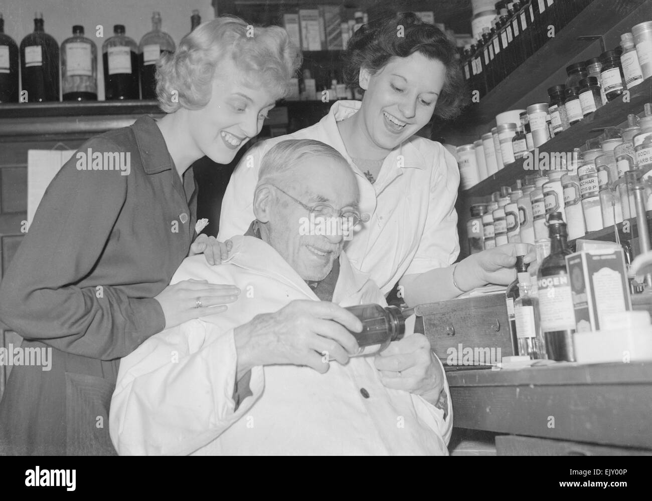 Signor Arthur Lawson 94 anno vecchia farmacia visto qui a lavorare con i suoi assistenti al suo dispensario. 1 Giugno 1952 Foto Stock