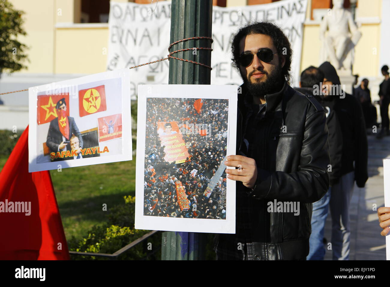 Atene, Grecia. Il 2 aprile 2015. Un manifestante trattiene una immagine dal funerale di 15 anno vecchio Berkin Elvan, e un'altra immagine mostra uno dei ostaggio assume, Şafak Yayla con il suo ostaggio. Una manciata di manifestanti hanno manifestato la loro solidarietà con le due persone uccise attivisti che aveva preso una procura in ostaggio in una Istanbul court house. Stavano chiamando per la verità nella uccisione di 15 anno vecchio Berkin Elvan che morì durante la Gezi proteste dopo essere stato colpito da un gas lacrimogeni canister dalla polizia. Credito: Michael Debets/Alamy Live News Foto Stock