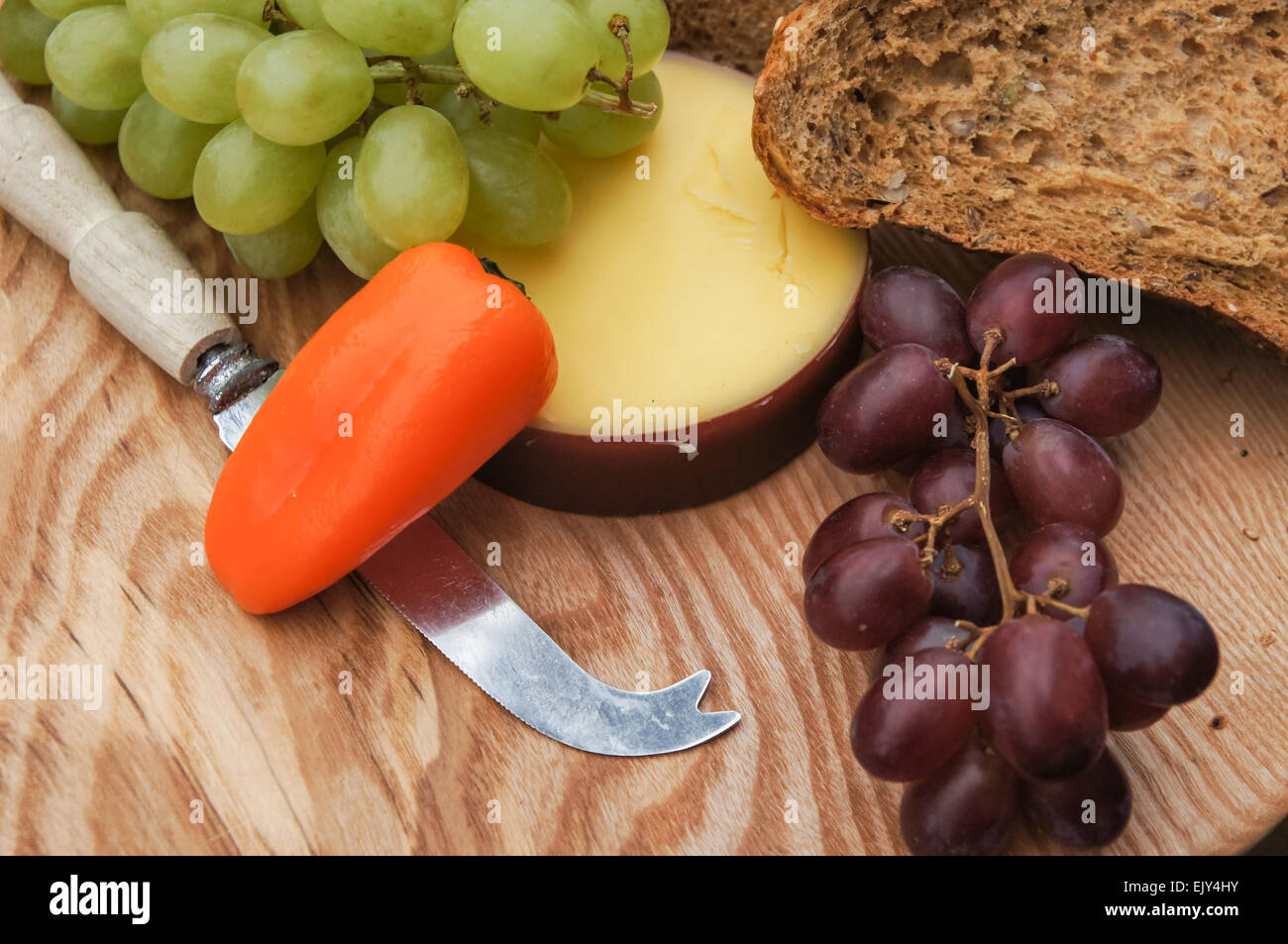 Formaggio, pane e uva sul tagliere di legno Foto Stock