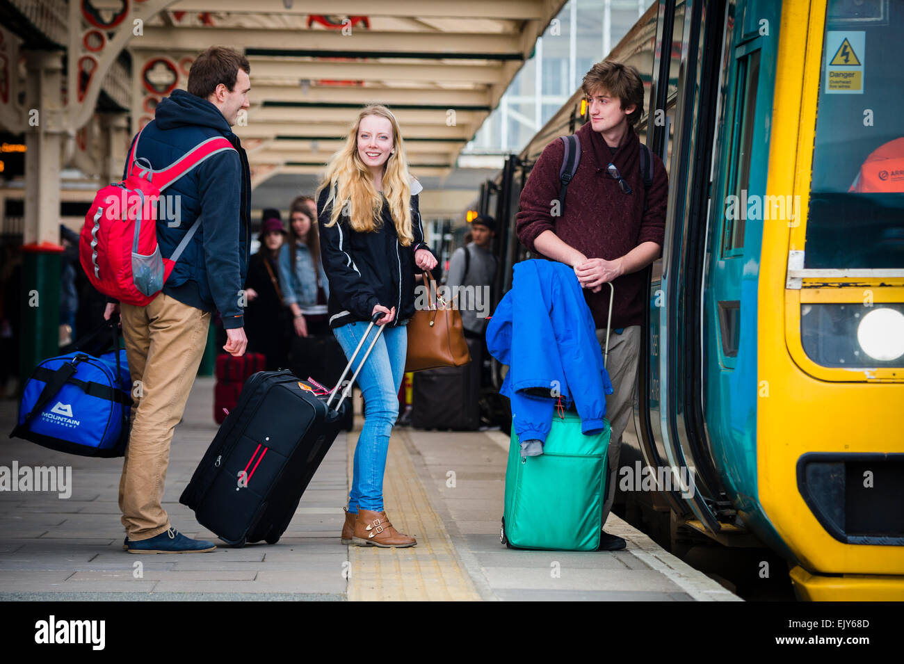 Trasporto pubblico: Gli Studenti Universitari con i loro bagagli per andare a casa la cattura di un Galles arriva il treno sulla piattaforma a Aberystwyth stazione ferroviaria alla fine del termine accademico, Marzo 2015 Foto Stock