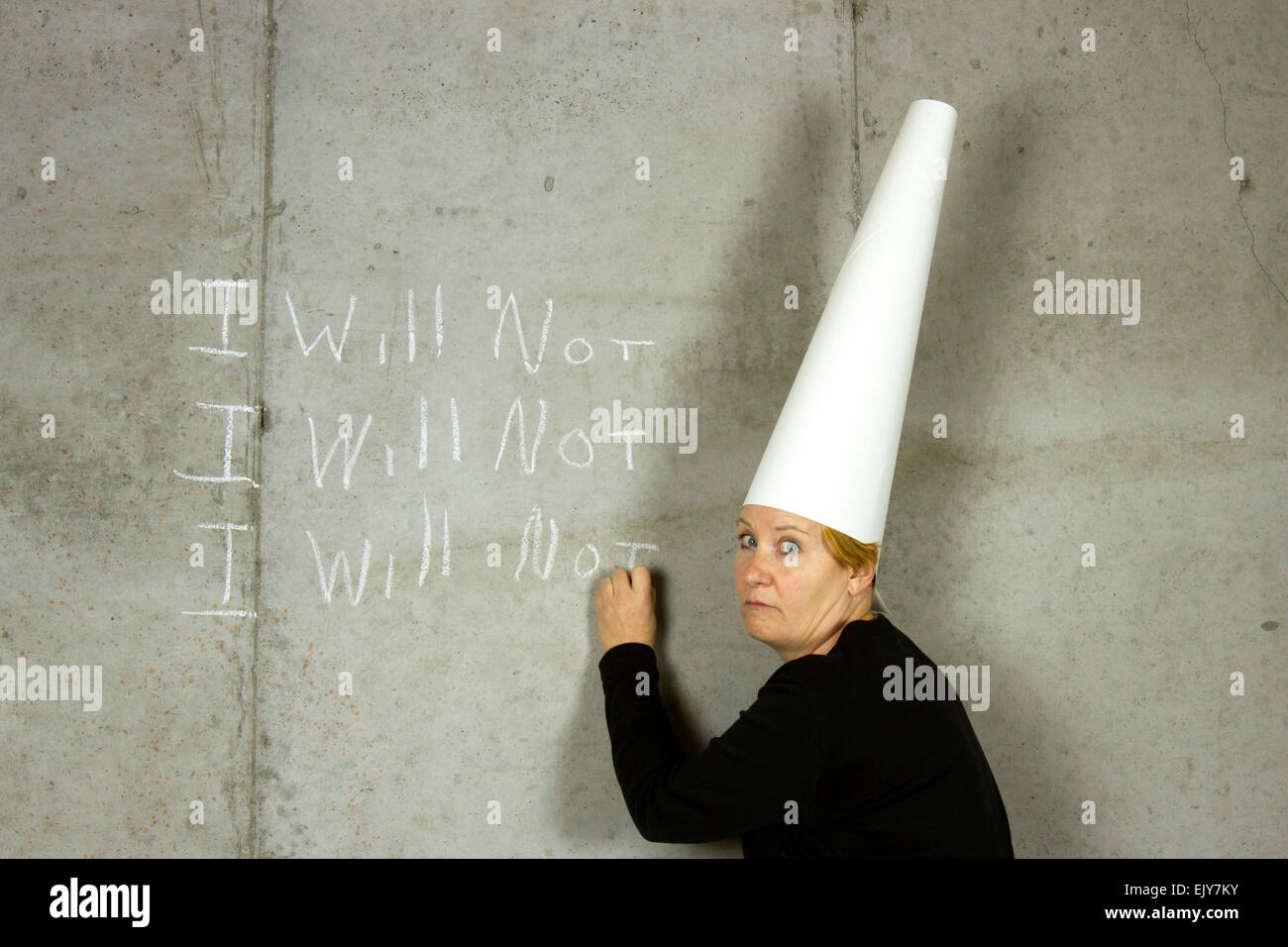 Donna che indossa un cappello dunce iscritto non mi su un muro di cemento Foto Stock