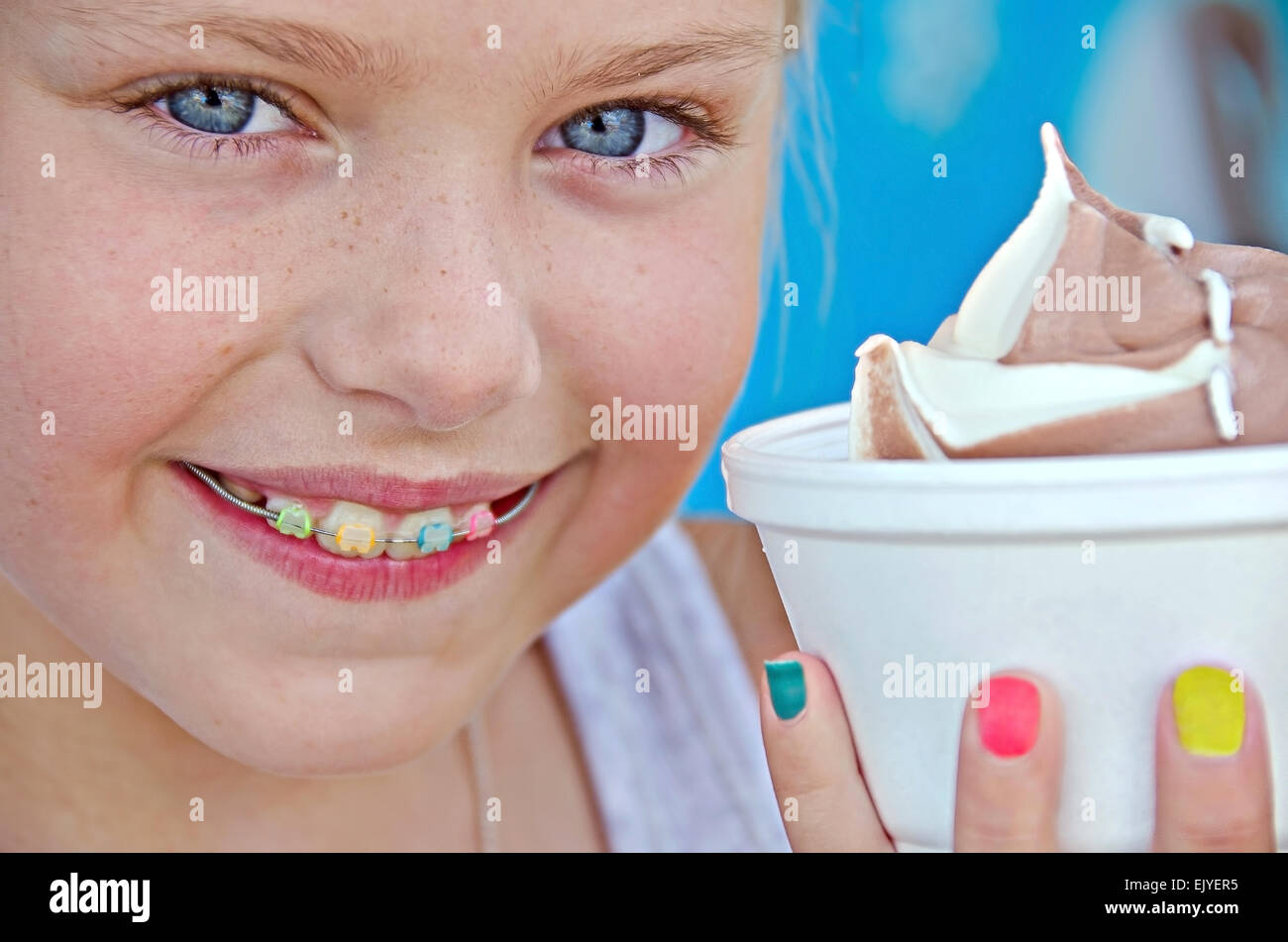 Ragazza giovane con sorriso ortodontico e gelato in una tazza. Foto Stock