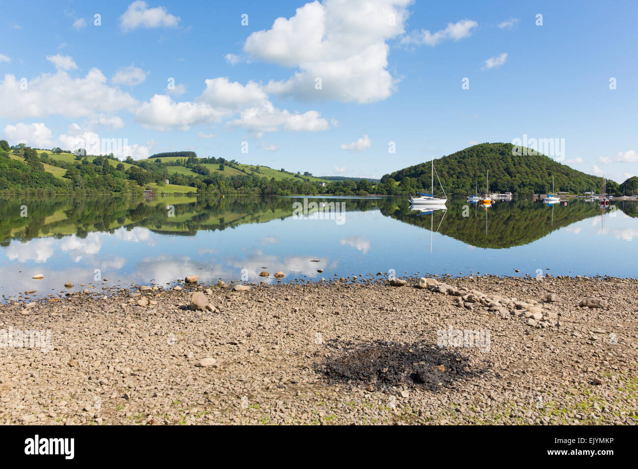 Barbecue ceneri dal bellissimo lago sulla tranquillità idilliaca mattinata estiva con il cloud riflessioni e cielo blu Ullswater Lake District UK Foto Stock