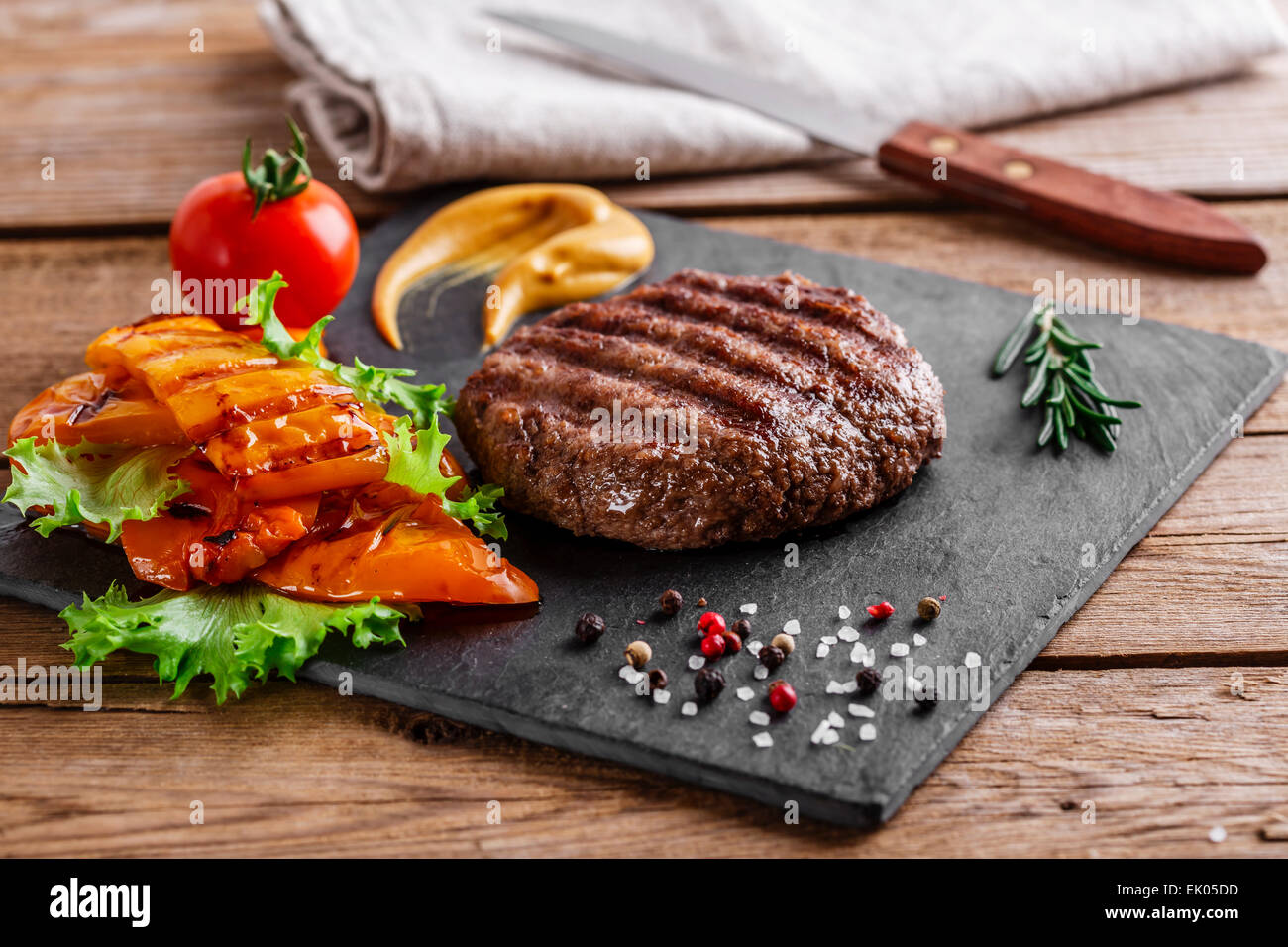 Burger grill con verdure e salsa su una superficie in legno Foto Stock