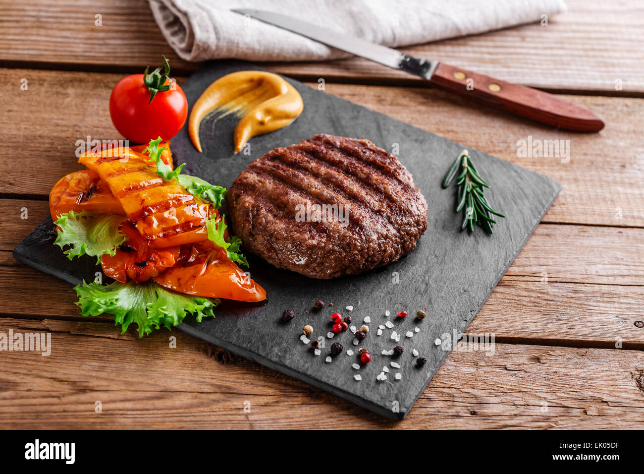 Burger grill con verdure e salsa su una superficie in legno Foto Stock