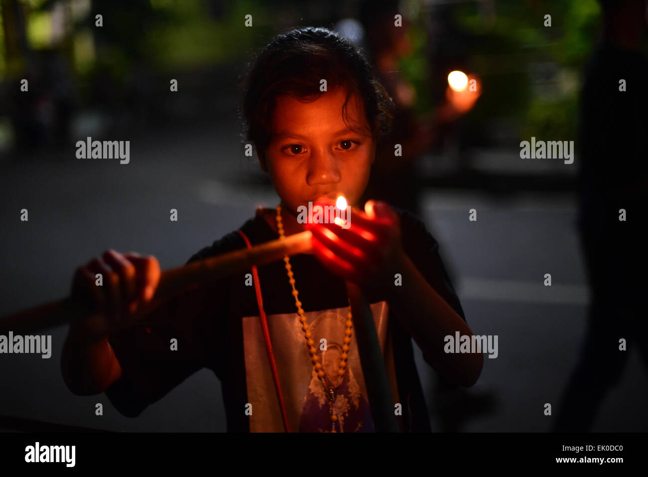 Larantuka, Indonesia. 3rd aprile 2015. Un bambino accende una candela come preparazione di una marcia devozionale di quattro ore nella celebrazione del Venerdì Santo a Larantuka, Flores Island, Indonesia. Migliaia di persone, comprese quelle di altre città e paesi, partecipano a una settimana intera di cerimonie per celebrare la settimana Santa nella piccola città di Larantuka, una delle città più influenti dell'Indonesia in termini di tradizioni cattoliche romane. Foto Stock