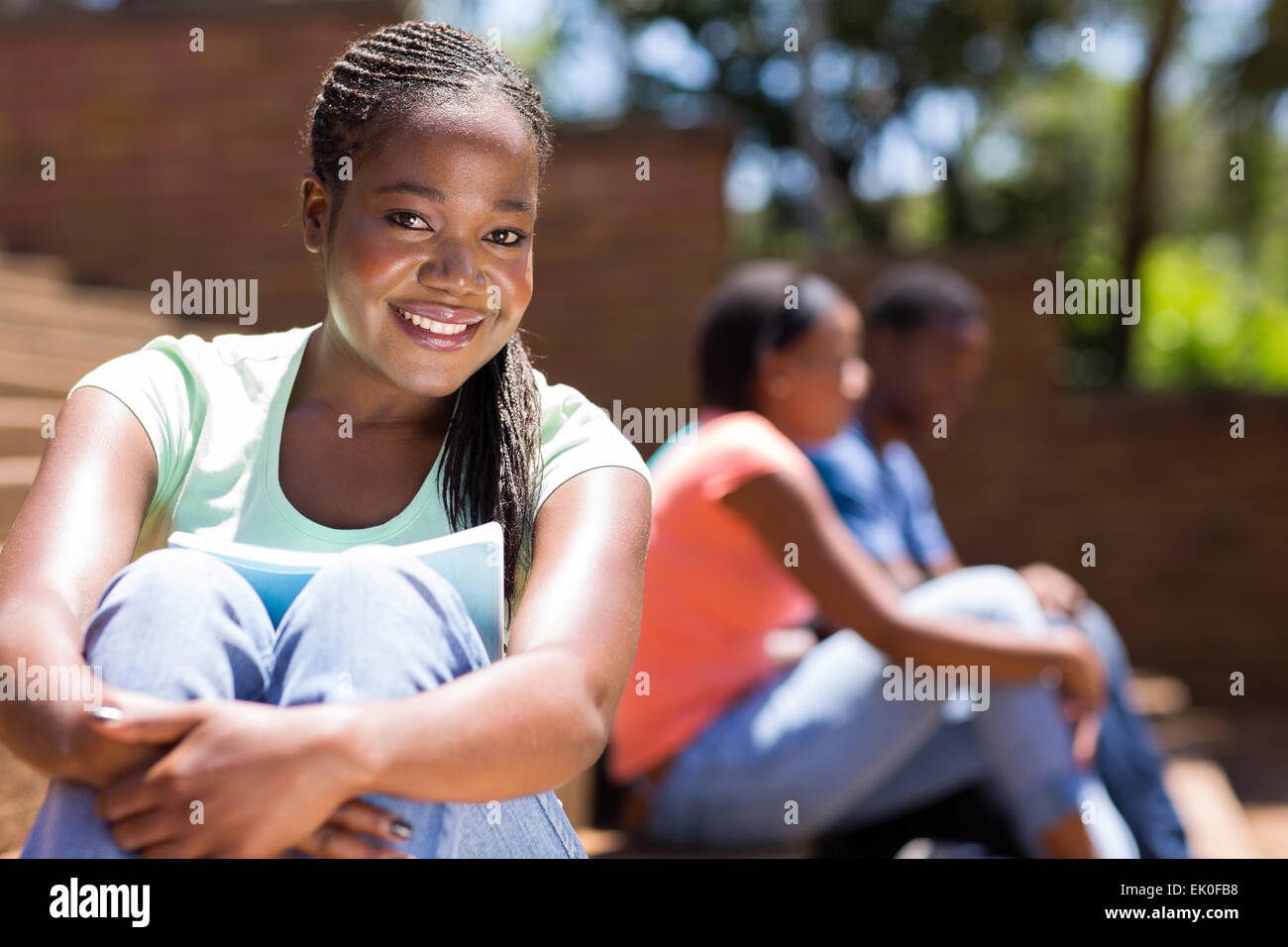 Splendida Afro American college ragazza seduta all'aperto Foto Stock