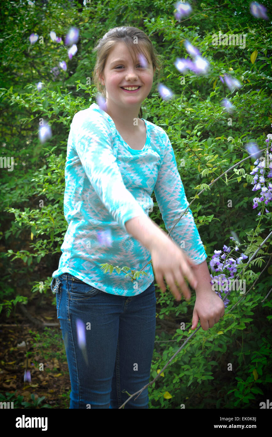 Un pre-teen getta petali durante una primavera foto riprese in un parco della città Foto Stock