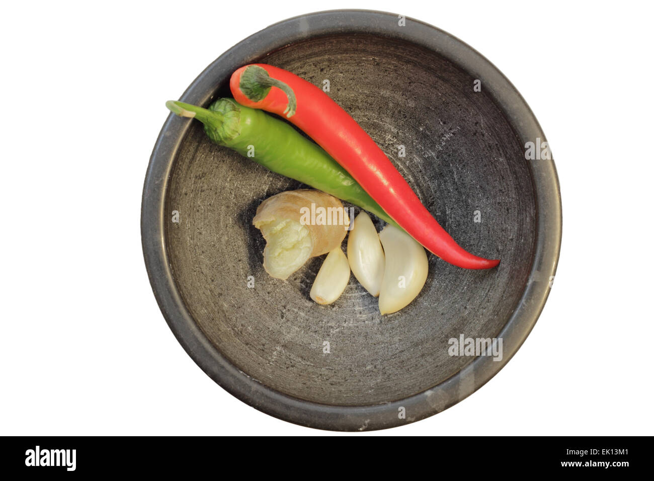 Lo zenzero, aglio e peperoncino (alcuni degli ingredienti di base della cucina tailandese in un mortaio, visto dal di sopra, isolato su bianco. Foto Stock