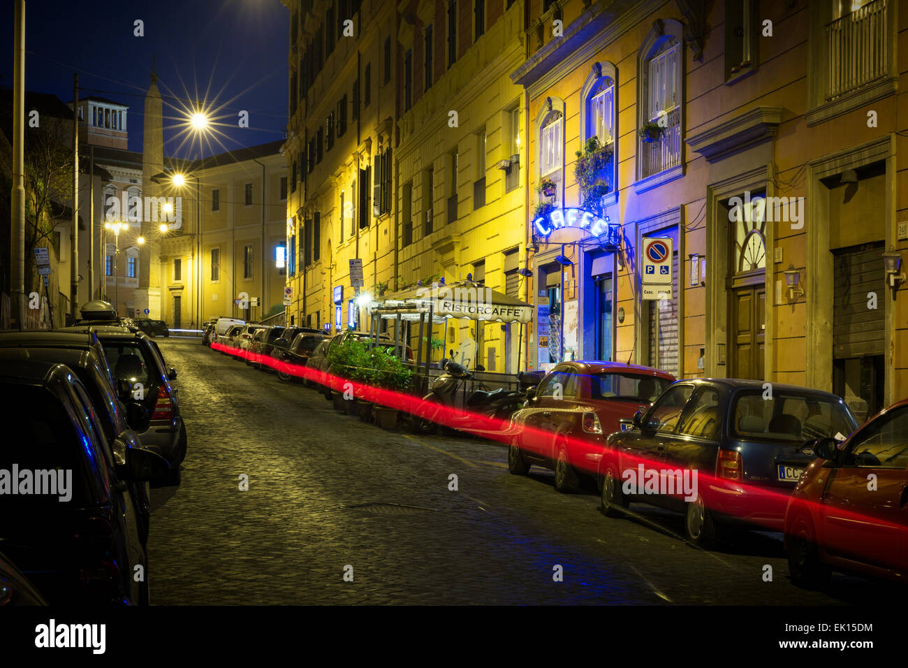 Backstreet con macchine parcheggiate e caffè a Roma di notte. Foto Stock