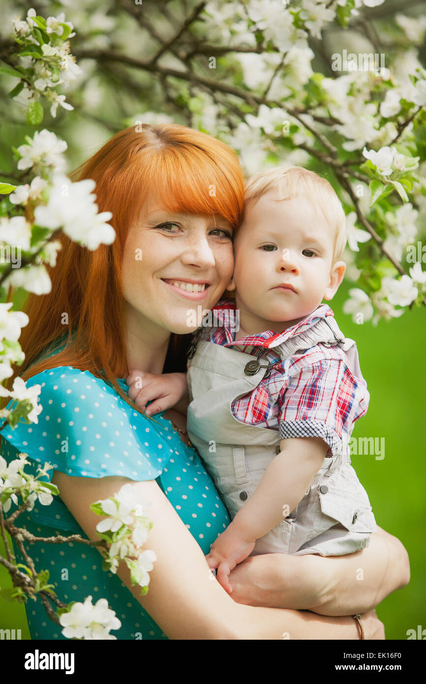Ritratto di happy madre e figlio nella primavera del giardino. Essi giocando e ridendo. Blooming apple-alberi. Concetto di famiglia. Foto Stock