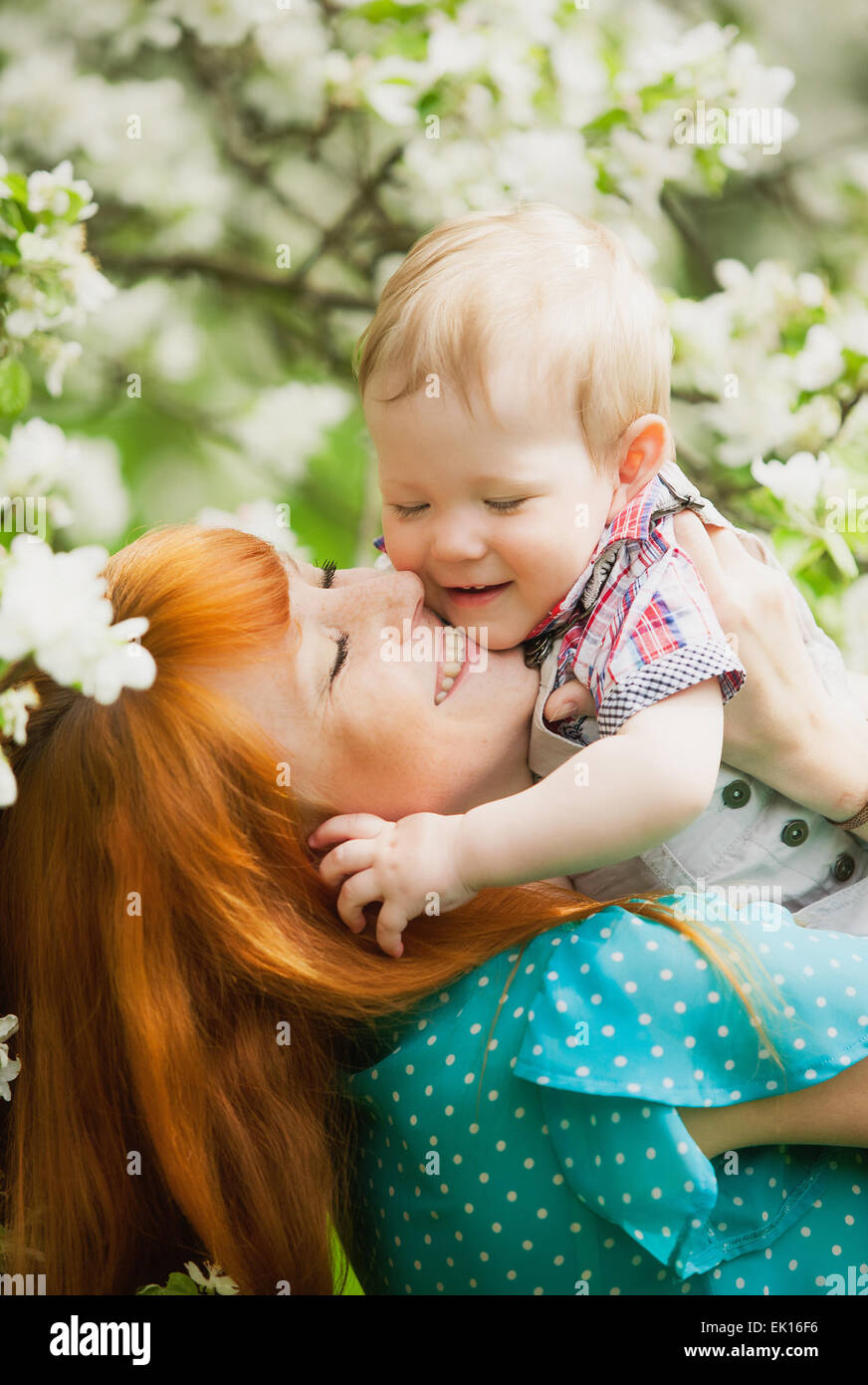 Ritratto di happy madre e figlio nella primavera del giardino. Essi giocando e ridendo. Blooming apple-alberi. Concetto di famiglia. Foto Stock