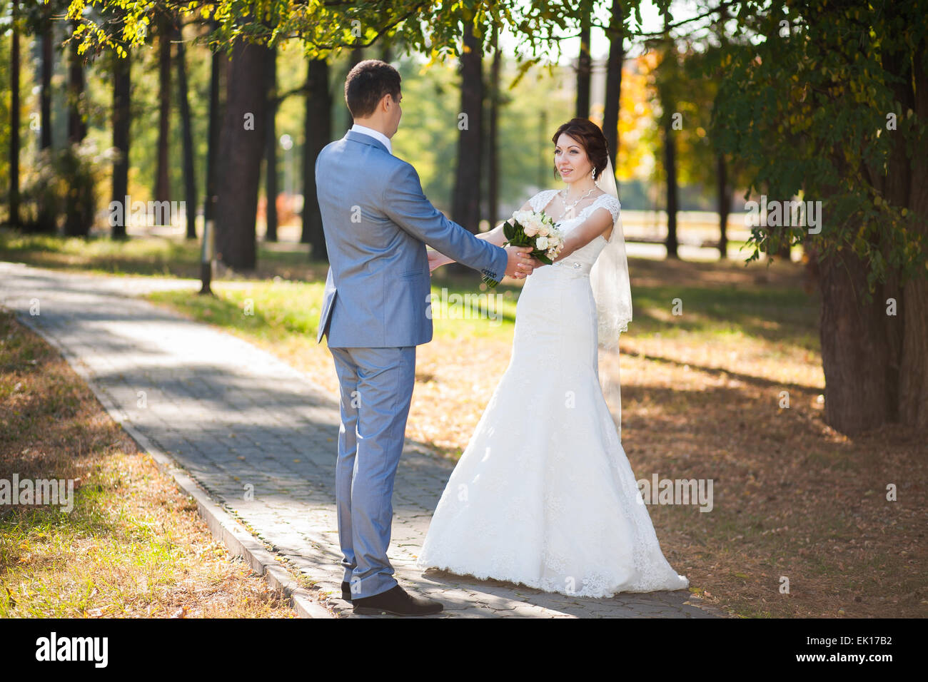 Felice sposa e lo sposo in piedi nel parco verde, baciare, sorridente, ridere, abbracciando. amanti in giorno di nozze Foto Stock