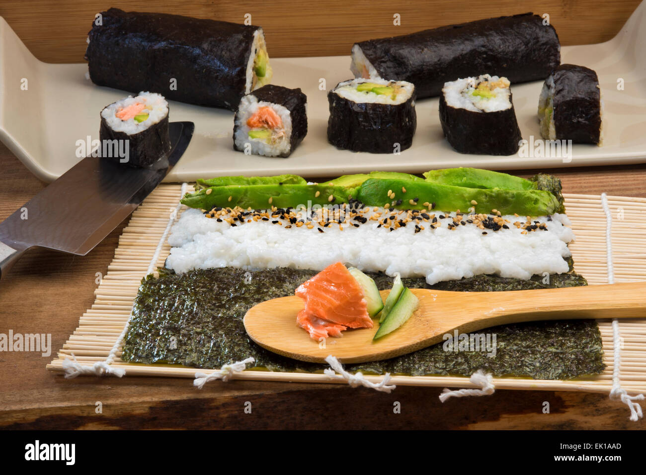 Rendendo il maki sushi rotoli con salmone, avocado e cetrioli Foto Stock