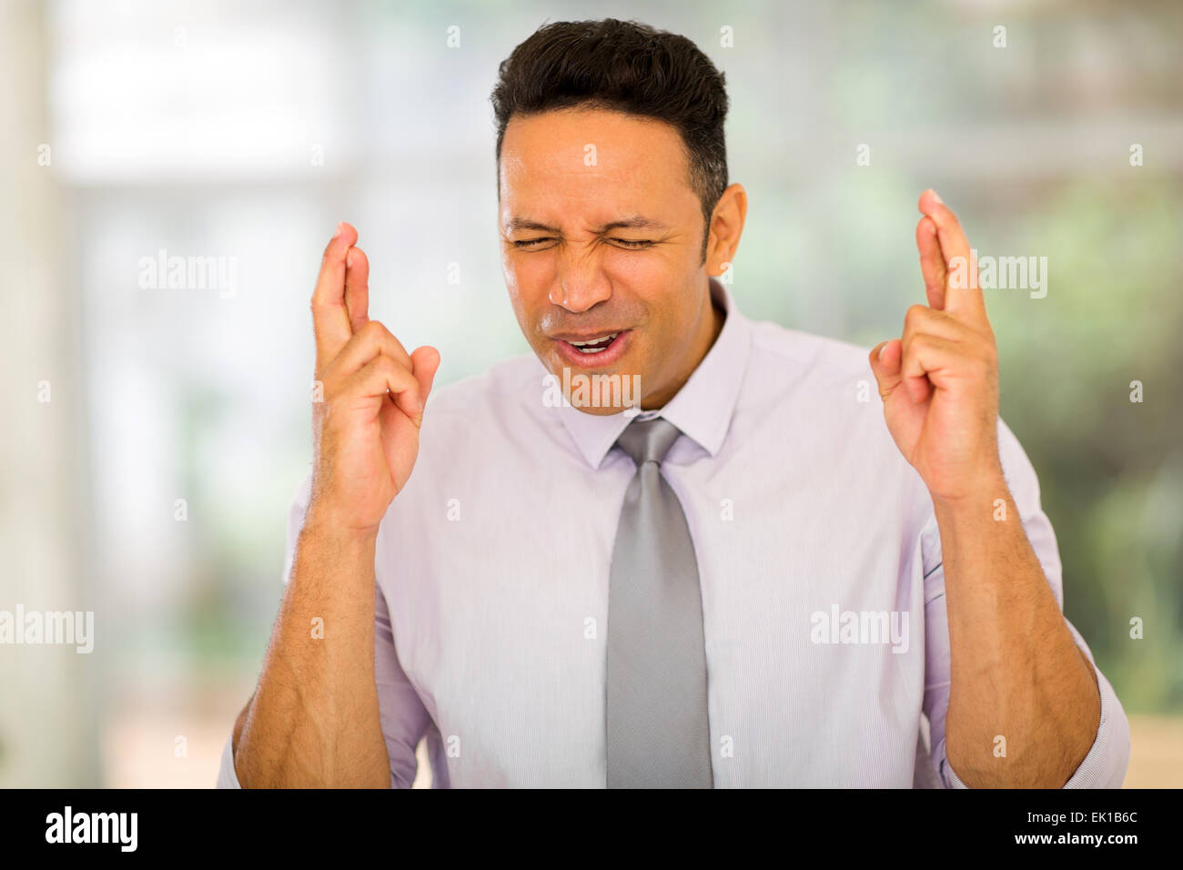 Lavoratore aziendale con le dita incrociate in un ufficio moderno Foto Stock