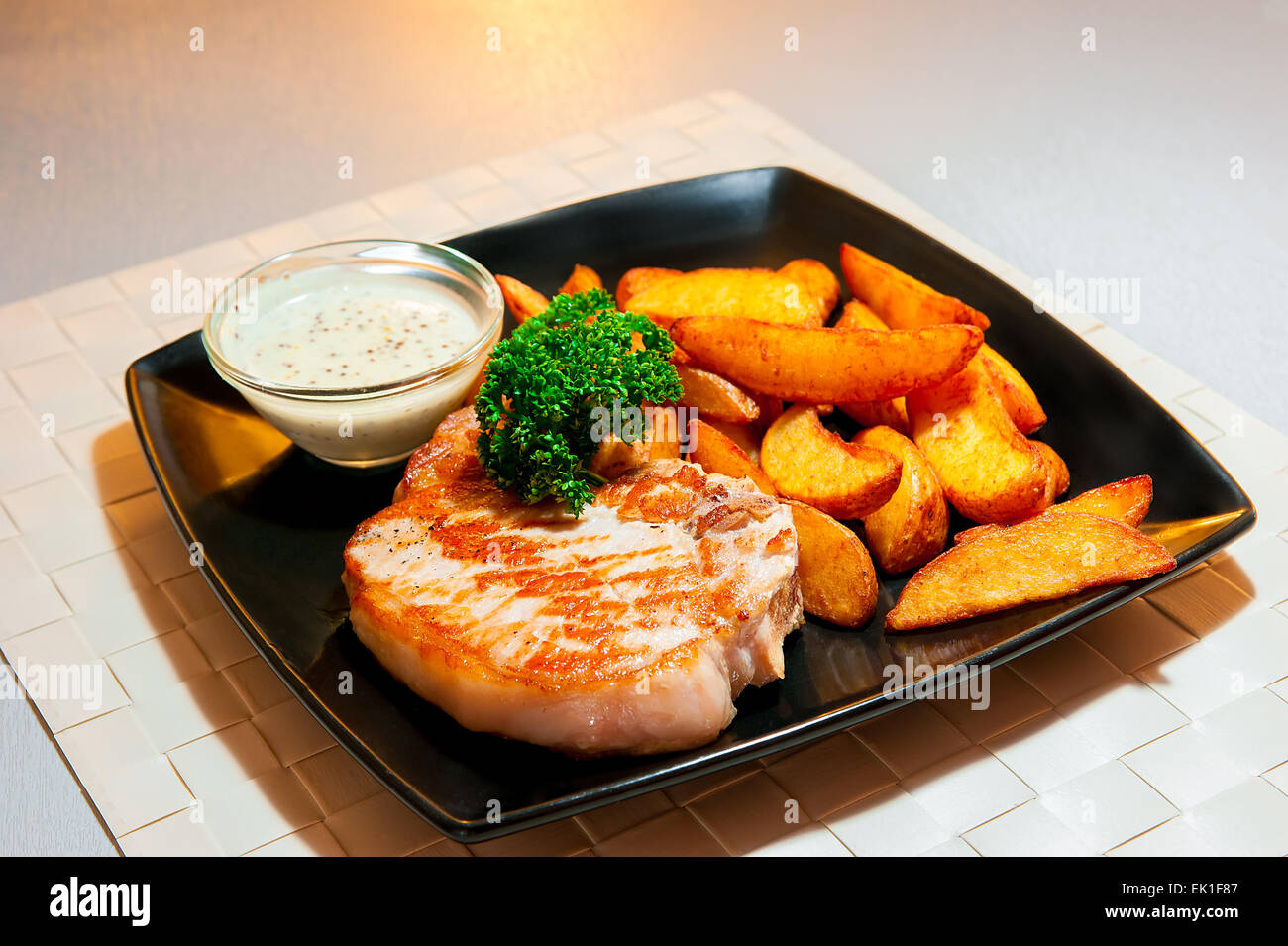 Deliziosa bistecca di carne di maiale con decorazione su una piastra nera Foto Stock