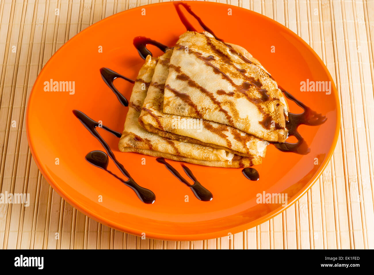 Il dessert crepes con salsa di cioccolato sulla piastra arancione Foto Stock