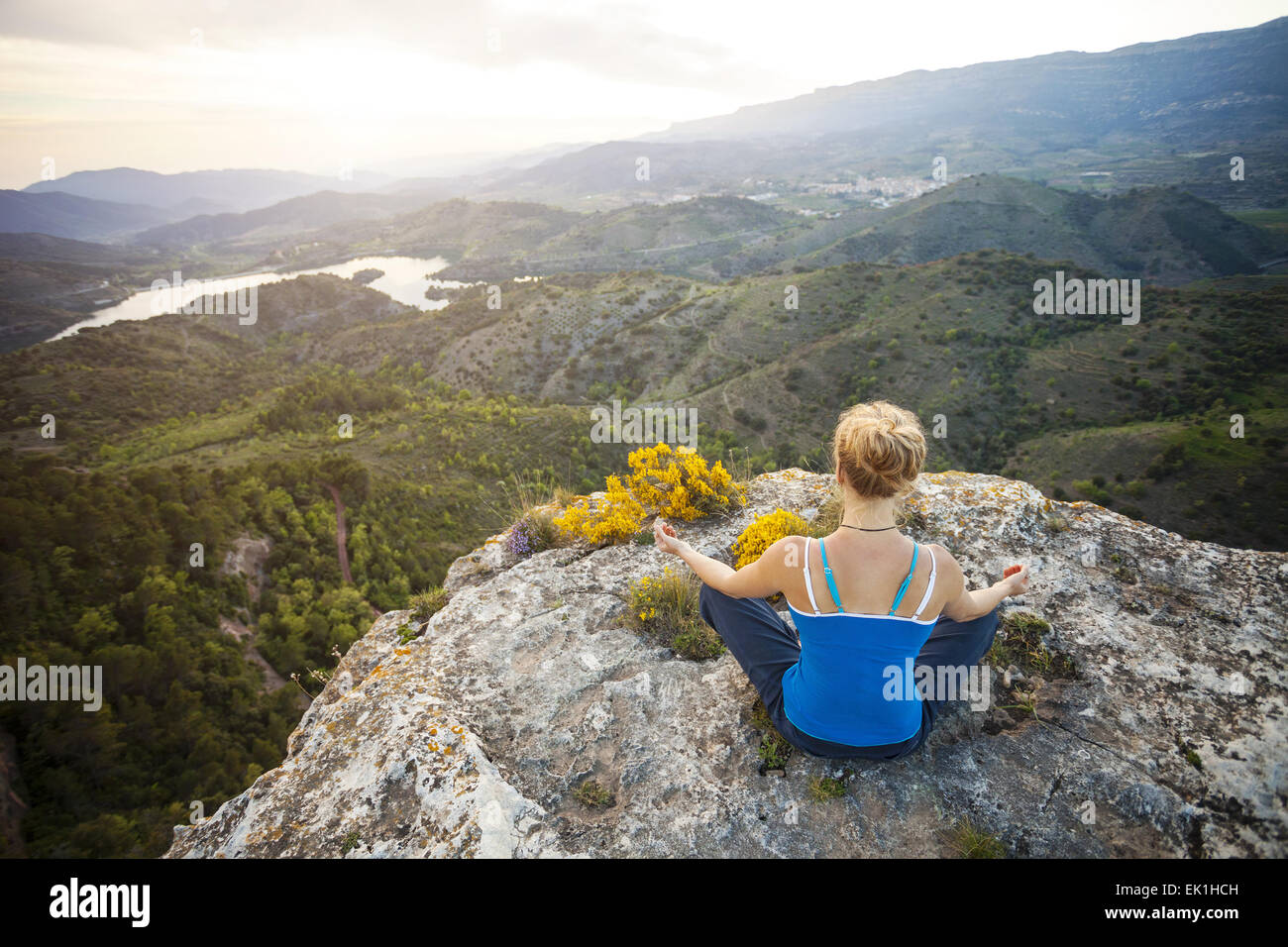 Giovane donna seduta su una roccia e godersi la vista della valle. La ragazza si siede nella posizione asana. Foto Stock