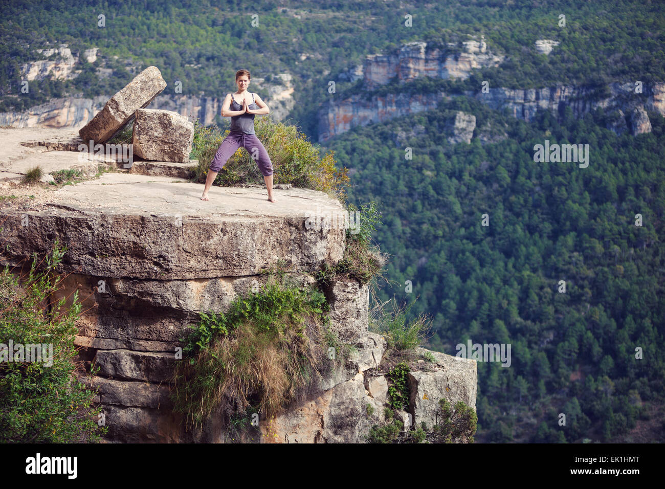 Giovane donna caucasica in piedi di yoga pone sulla cima della scogliera Foto Stock