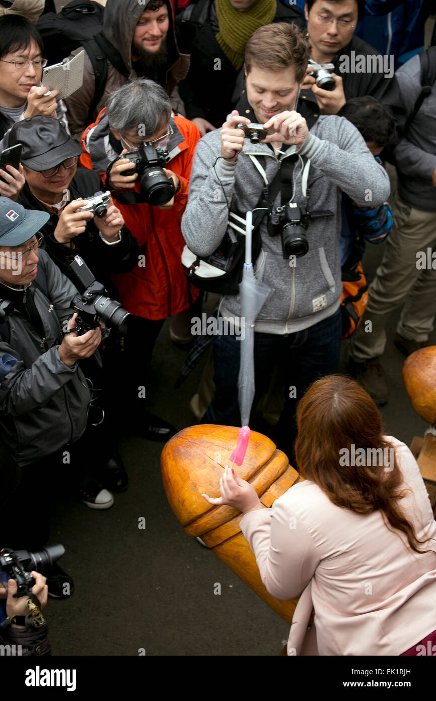 Un visitatore pone per le telecamere di fronte ad un grande fallo durante il Festival Kanamara a Kawasaki il 5 aprile 2015. Il Kanamara Matsuri o il festival del fallo di acciaio è stato avviato da prostitute che ha voluto pregare per la protezione contro le malattie sessualmente trasmissibili. La gente ora desiderate per una facile erogazione, matrimonio e sposato-giovane armonia. Il festival si tiene la prima domenica di aprile presso il santuario Kanayama. Essa è diventata un'attrazione turistica ed è utilizzato per raccogliere fondi per le associazioni di beneficenza di HIV. © Rodrigo Reyes Marin/AFLO/Alamy Live News Foto Stock