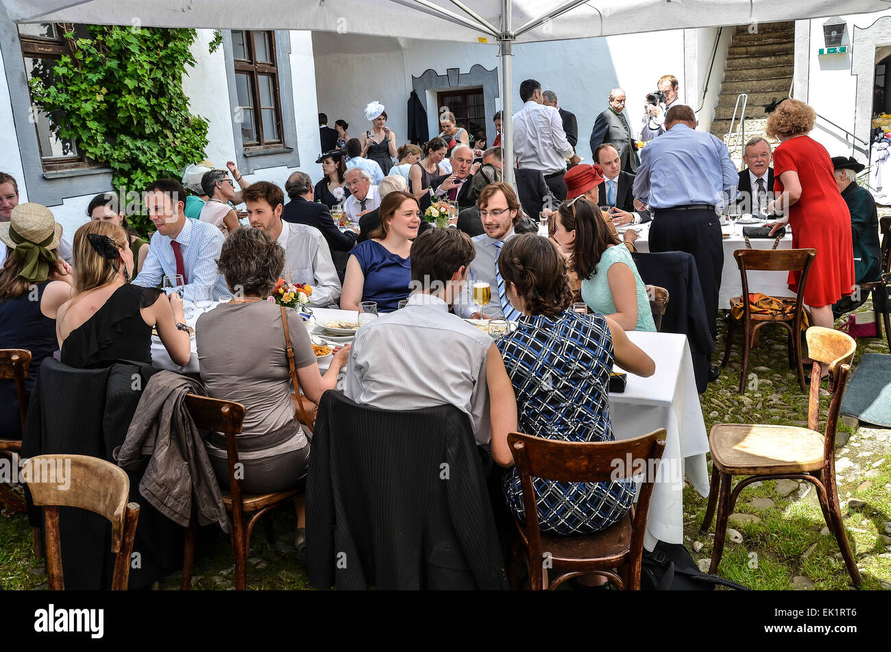 Dopo il matrimonio cerimonia party all'aperto agli ospiti di nozze abiti da sposa colorati fantasia cappelli Cappelli mangiare bere parlando Foto Stock