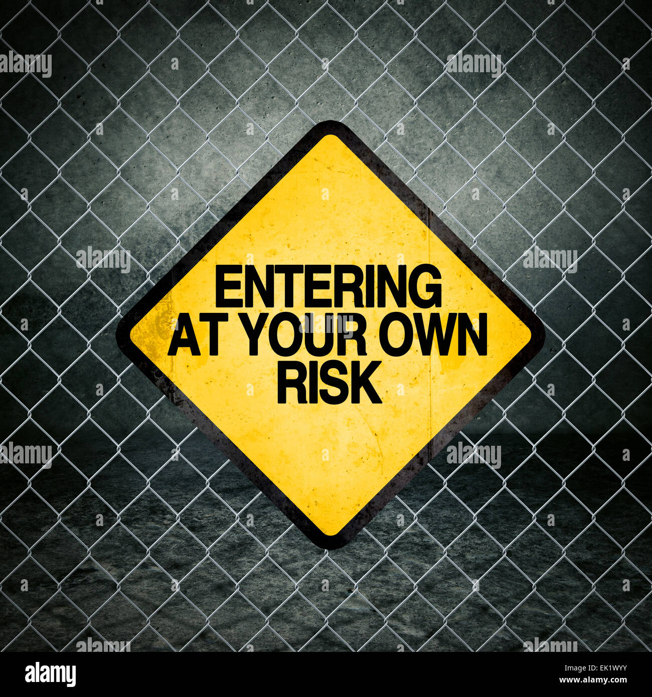 Entrando a proprio rischio Grunge simbolo giallo di avvertimento sulla recinzione ad anelli di magazzini industriali Foto Stock