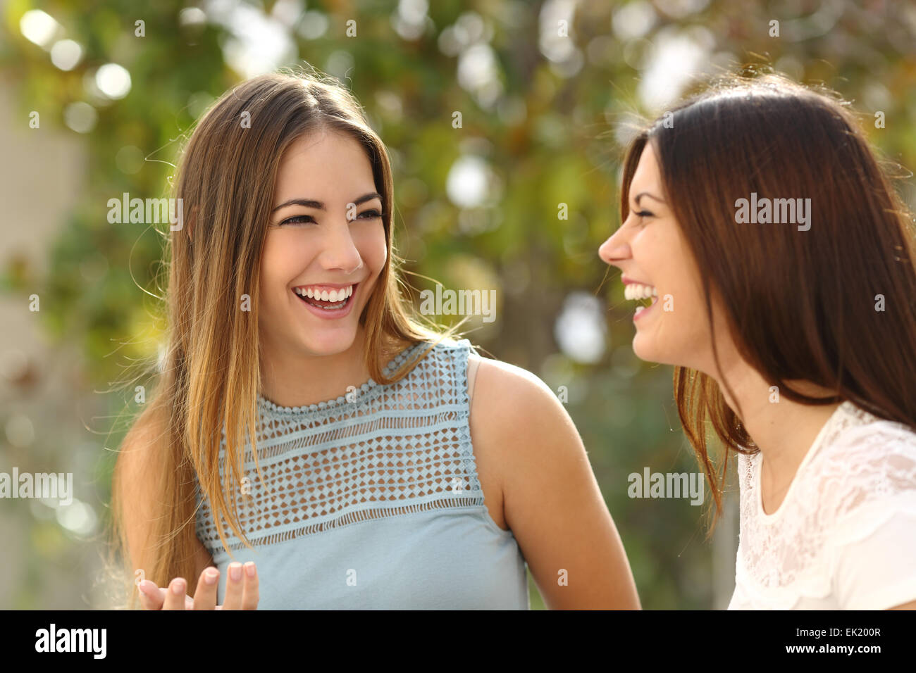 Felici donne parlare e ridere in un parco con uno sfondo verde Foto Stock