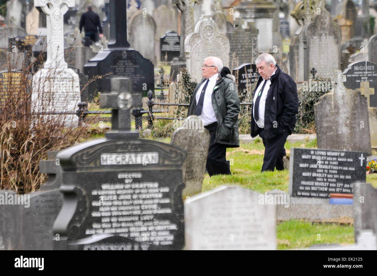 Belfast, Irlanda del Nord, Regno Unito. 5 Aprile, 2015. Due uomini vestiti di bianco e camicie, legami neri e nero si adatta a piedi attraverso un antico cimitero Credit: stephen Barnes/Alamy Live News Foto Stock