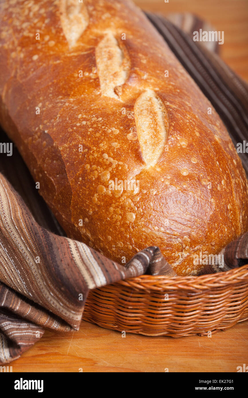 Pane casereccio pane di pasta acida in un cestino del pane foderato con un marrone striato canovaccio Foto Stock