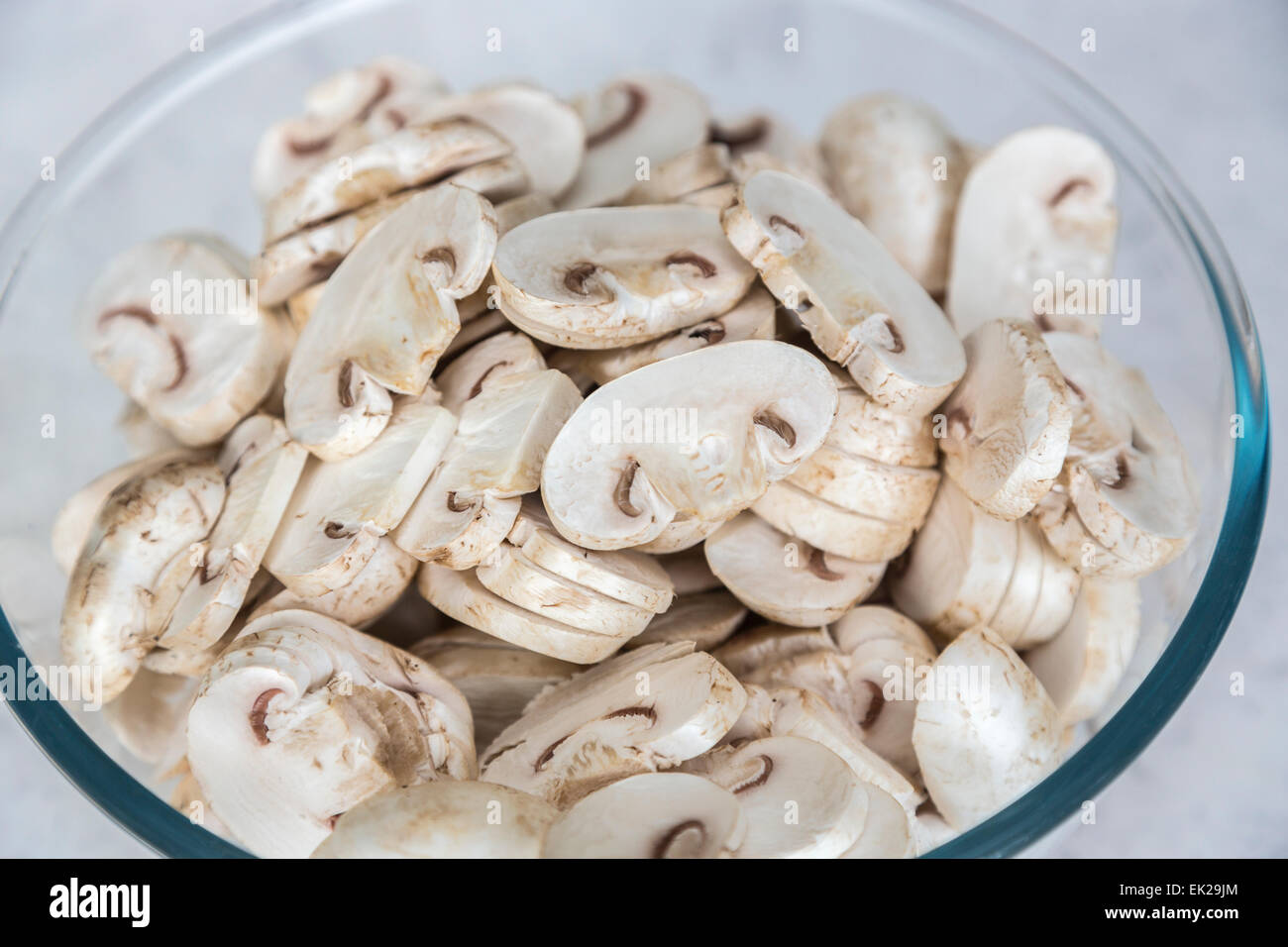 Home ingredienti di cucina - un bicchiere o una ciotola di pyrex di materie non cotti preparati fette di funghi prataioli pronto per l'uso in cucina Foto Stock