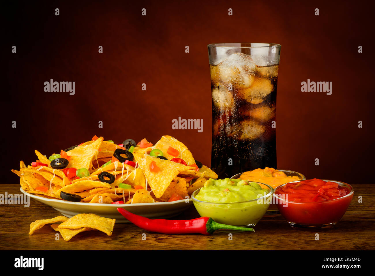 Piastra di nachos, salsa, chesse e guacamole dip e bevanda di cola Foto Stock
