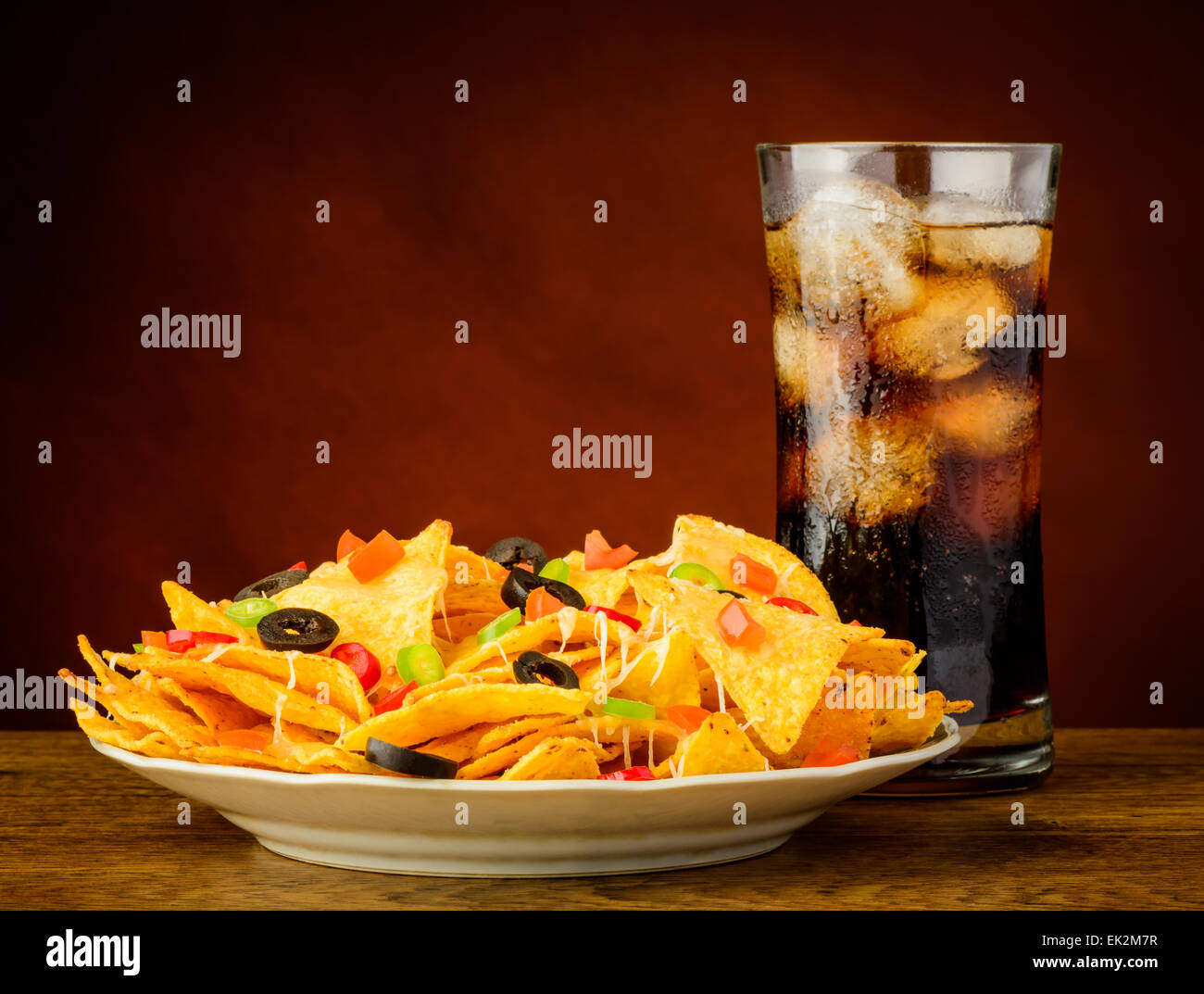 I nachos su un piatto è servito con un bicchiere di freddo bevanda di cola Foto Stock