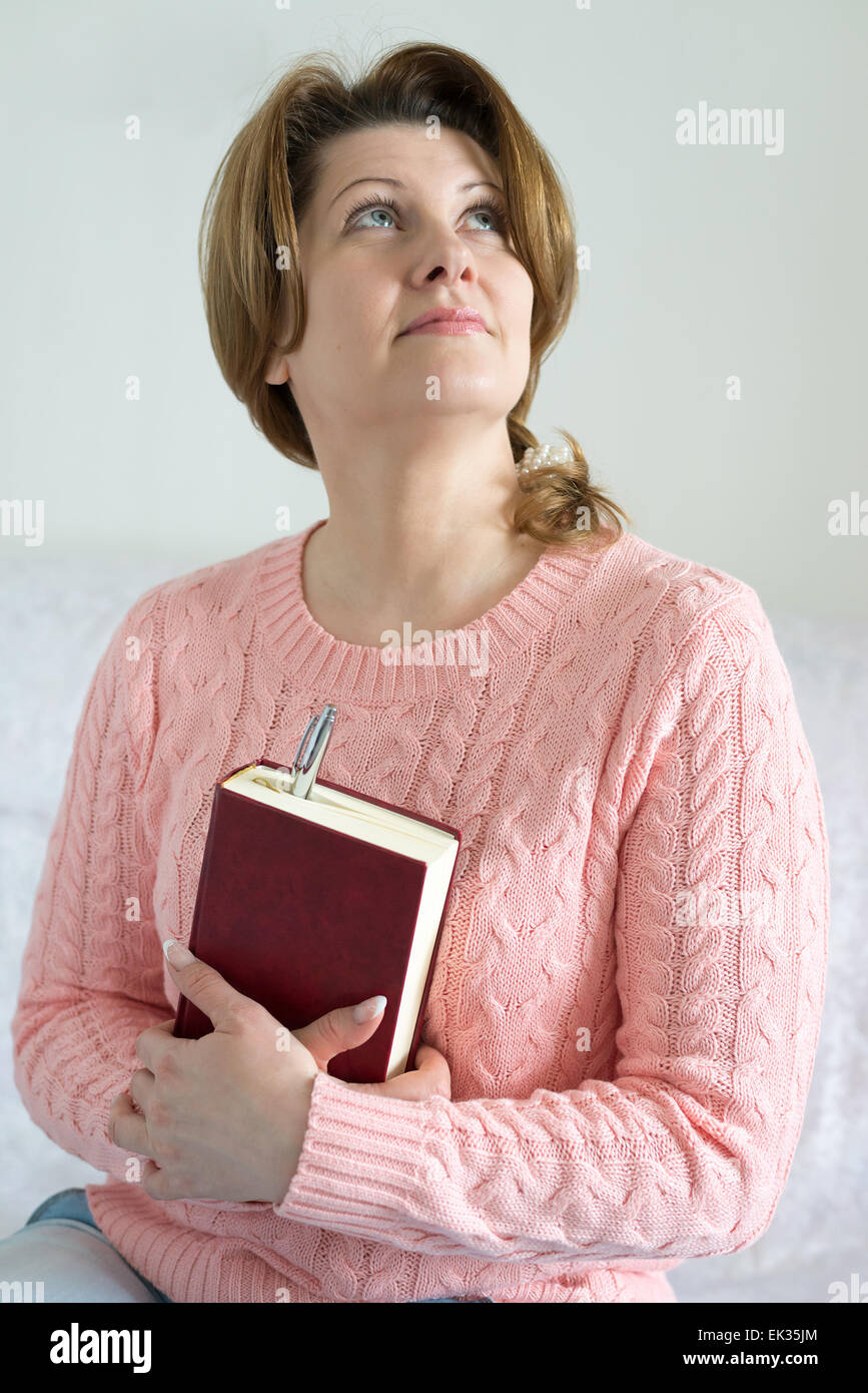 Donna positivo con un notebook e penna in una mano Foto Stock