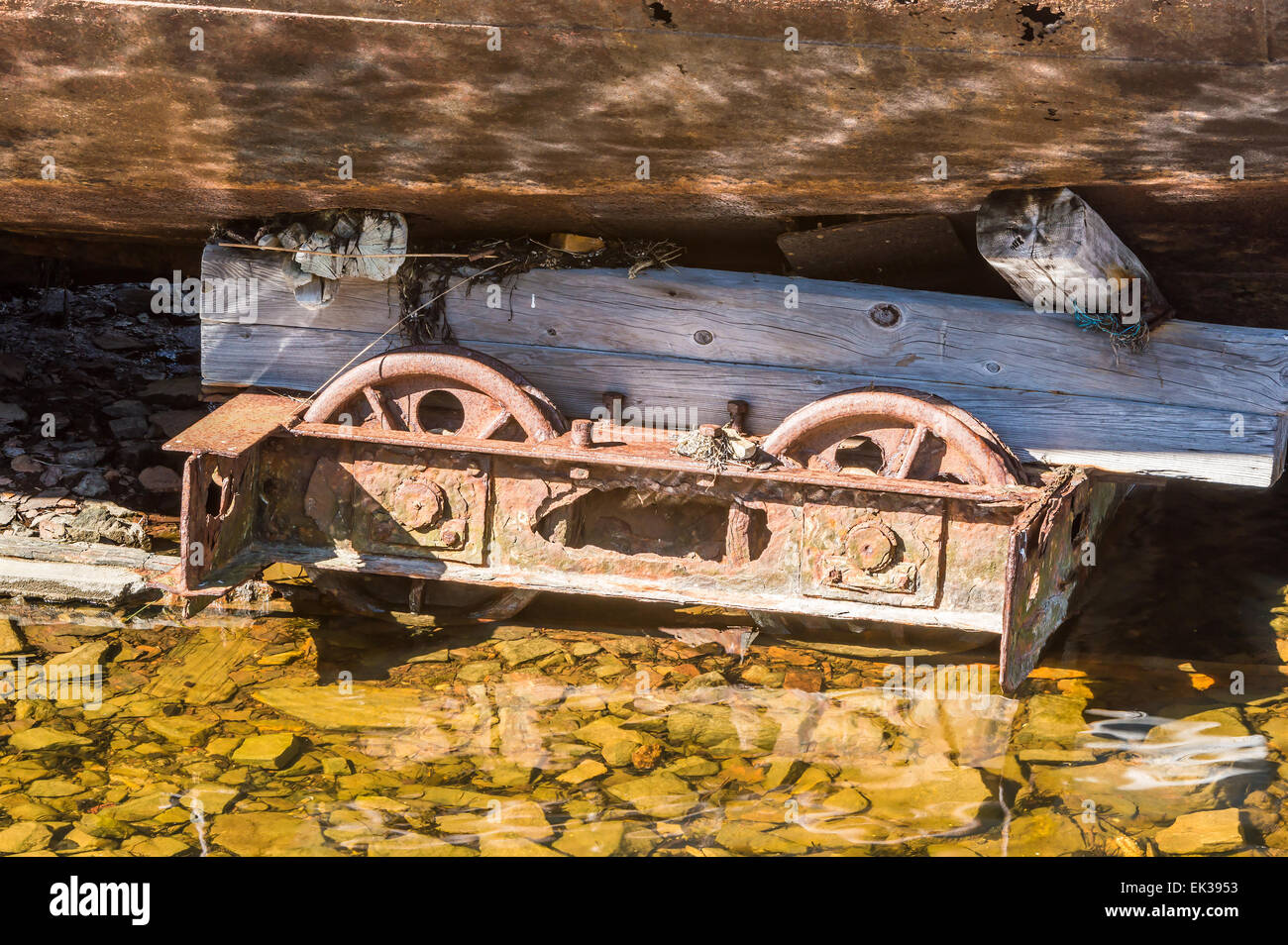 Vecchio arrugginito ruote di ferro da sotto un naufragio. Acqua di mare in primo piano. Riflessioni sulla chiglia. Foto Stock