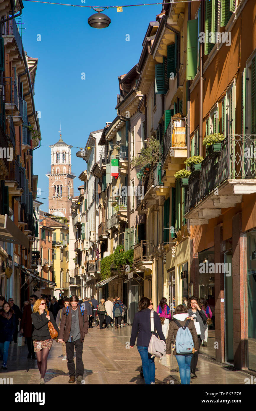 I turisti e gli amanti dello shopping lungo Via Giuseppe Mazzini con Torre dei Lamberti al di là, Verona, Veneto, Italia Foto Stock