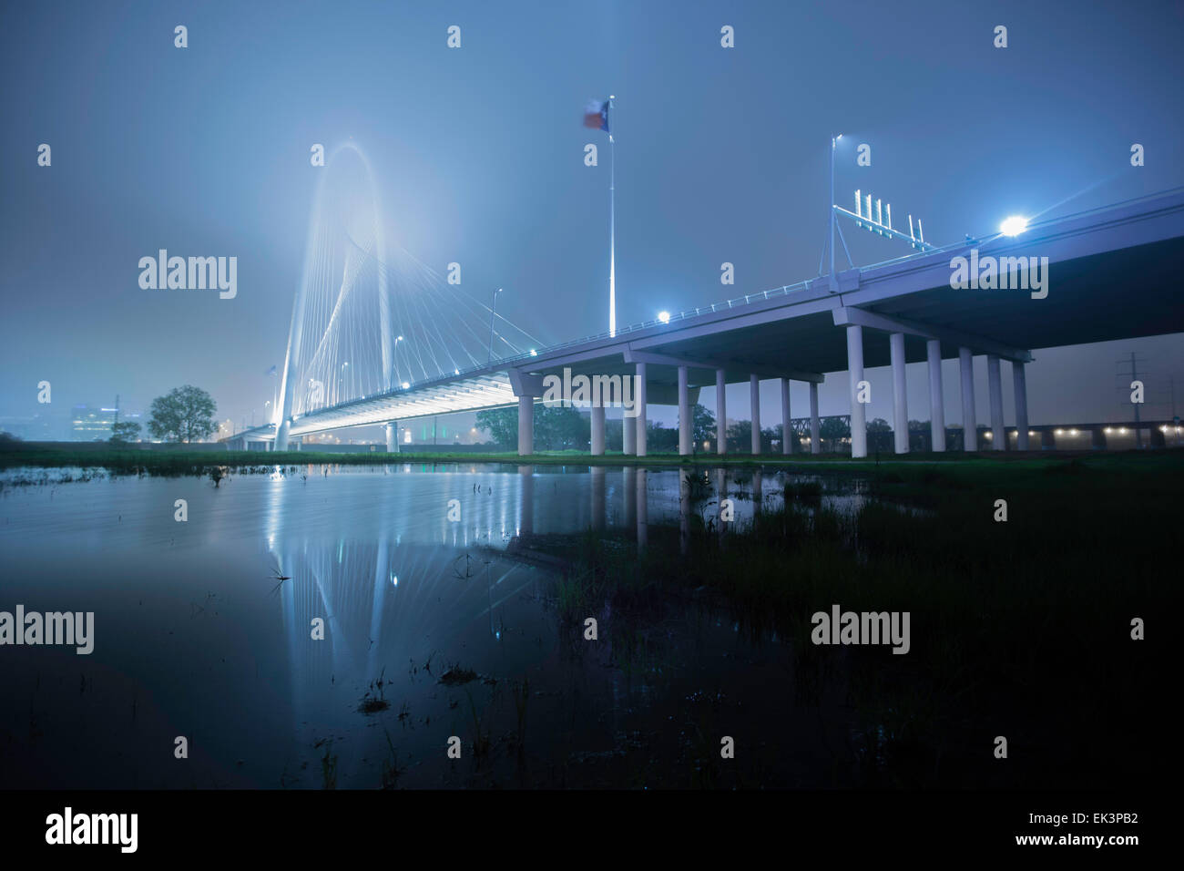 Ampia esposizione a lungo colpo di Margaret Hunt Hill Bridge nel centro di Dallas Texas in una nebbiosa notte di nebbia con una riflessione. Foto Stock