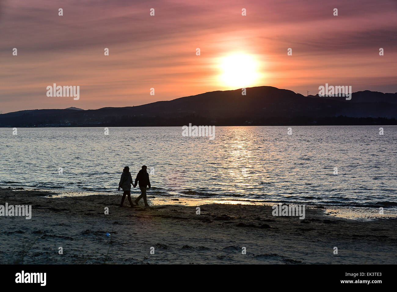 Lough Swilly, County Donegal, Irlanda. 6 Aprile, 2015. In Irlanda il meteo: un paio di camminare sulla spiaggia di Fahan alla fine di un soleggiato e caldo il lunedì di Pasqua in Donegal. Credito: George Sweeney/Alamy Live News Foto Stock