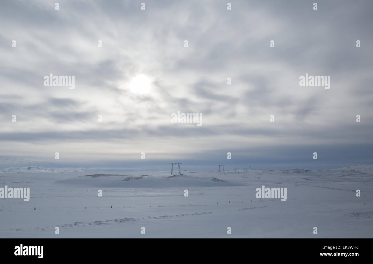 Elettricità tralicci punteggiano il paesaggio innevato in Islanda Foto Stock