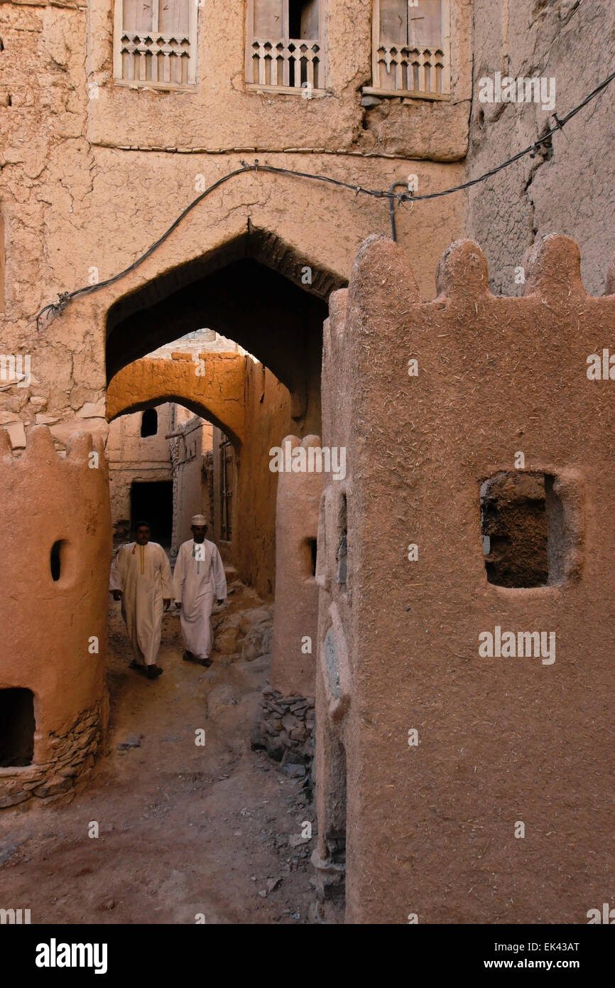 Gli uomini in dishdashas a piedi nella vecchia sezione di Al-Hamra, Oman Foto Stock