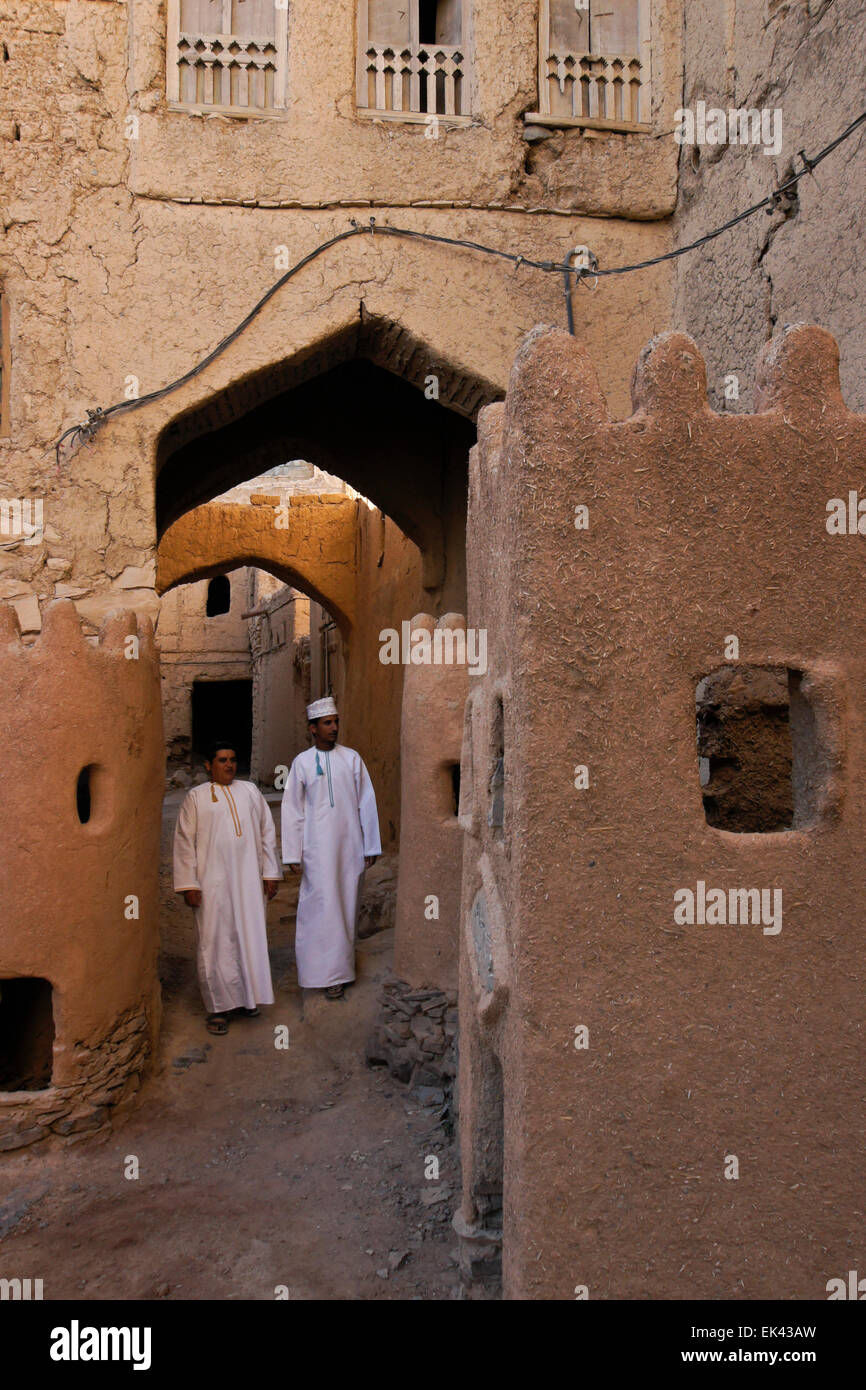 Gli uomini in dishdashas a piedi nella vecchia sezione di Al-Hamra, Oman Foto Stock