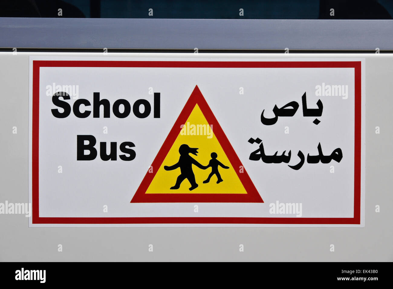 Scuola bus segno di attenzione in inglese e arabo Foto Stock