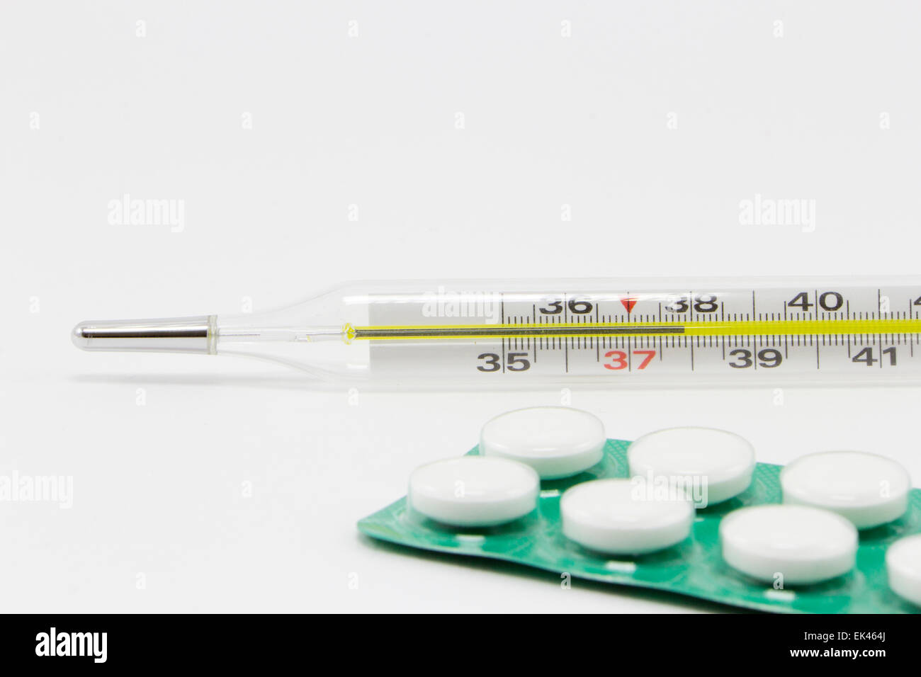 Pillole di bianco e un termometro su sfondo bianco Foto Stock