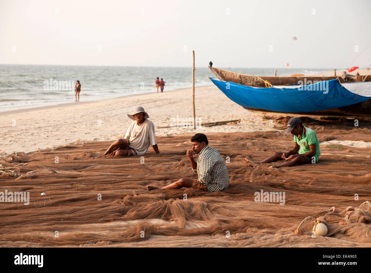 I pescatori a riparare le net sulla spiaggia in Benaulim, Goa, India, Asia Foto Stock