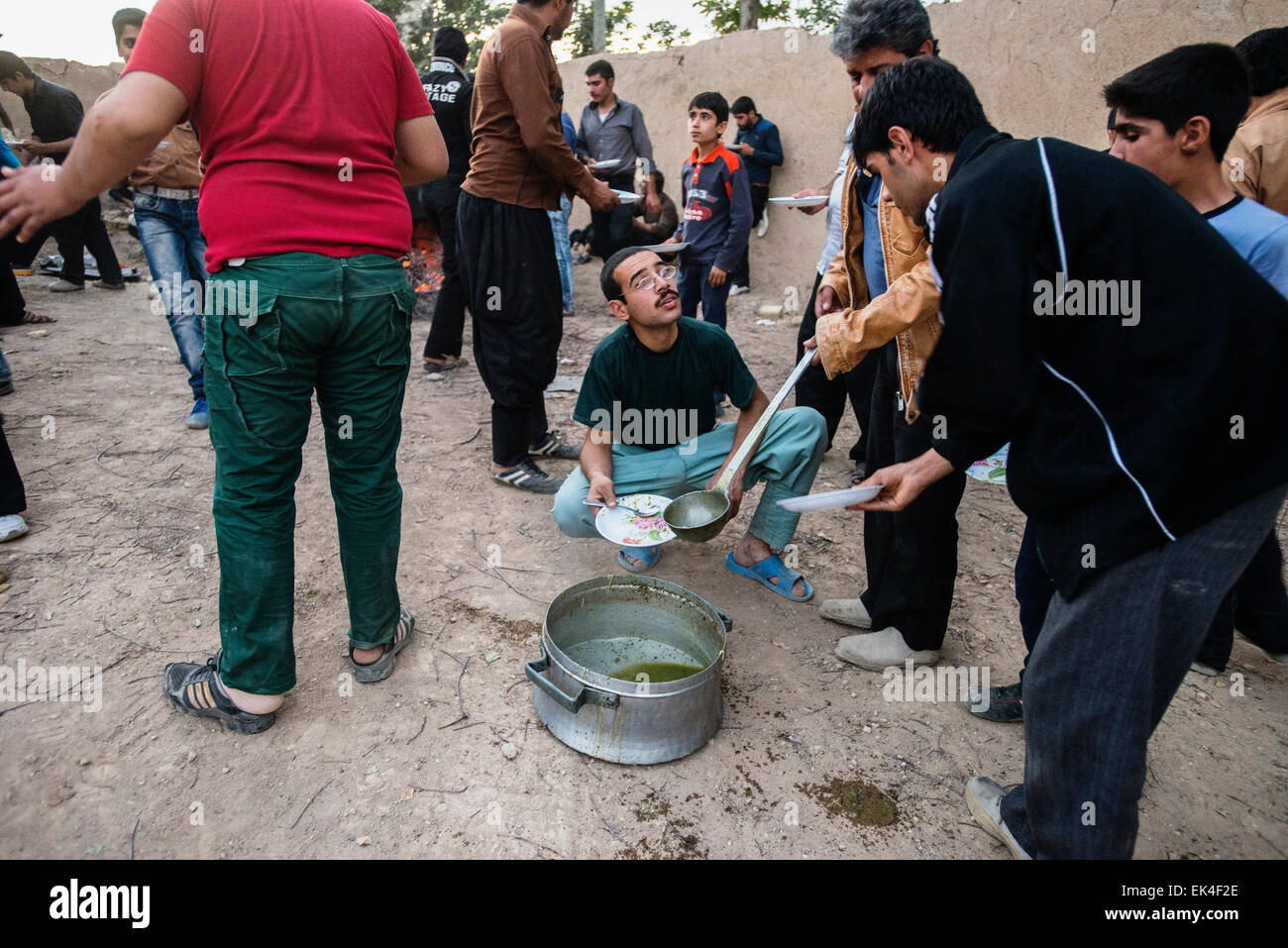 Gli uomini rituale serve il pranzo Minestra di fagioli, i thread e le verdure per i partecipanti della prova di Tazieh, teatro rituale del giorno di Ashura, nel villaggio vicino a Isfahan, Iran Foto Stock