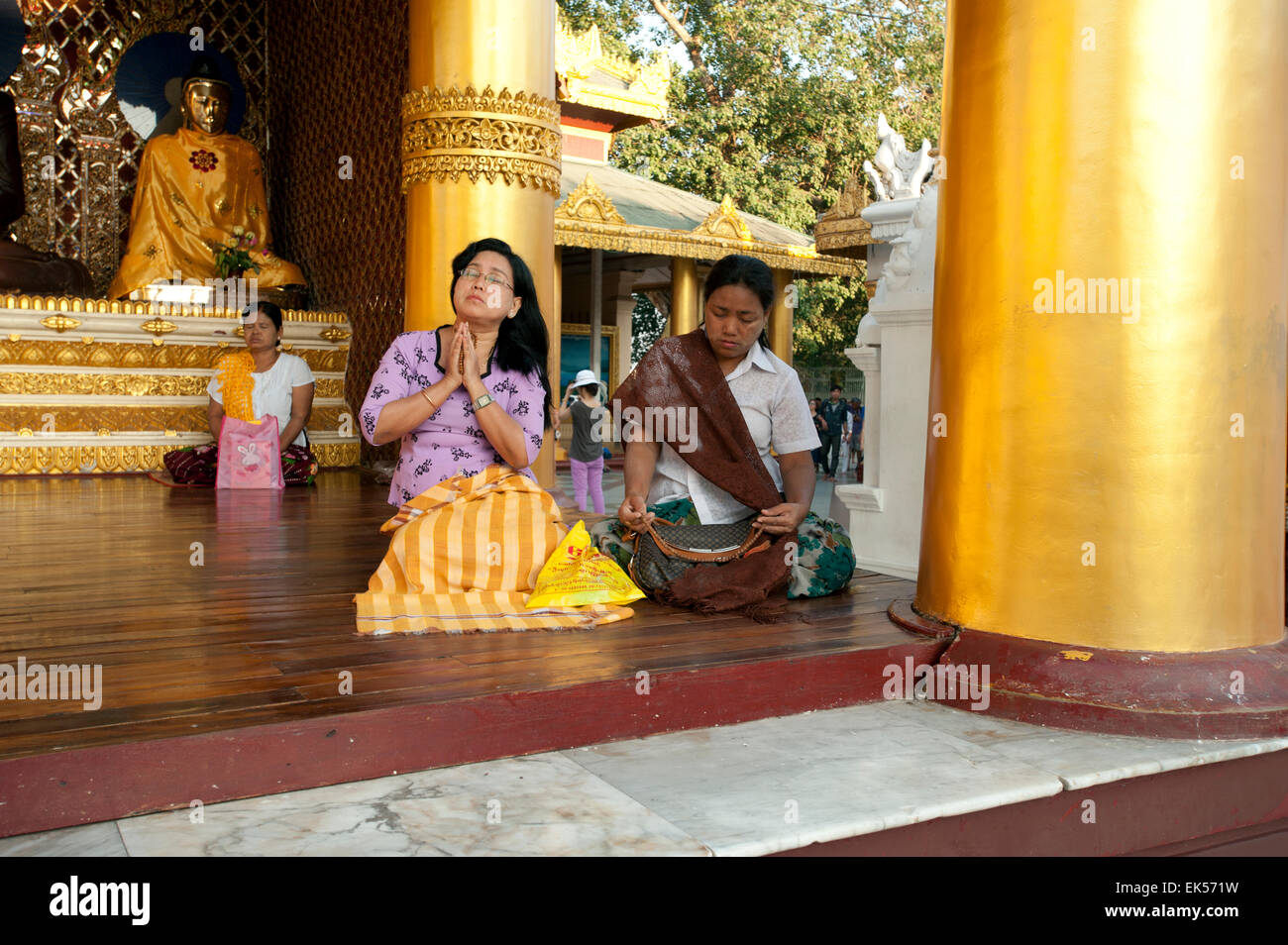 Adoratori di sedersi in preghiera su una piattaforma alla Shwedagon pagoda in Yangon Myanmar Foto Stock